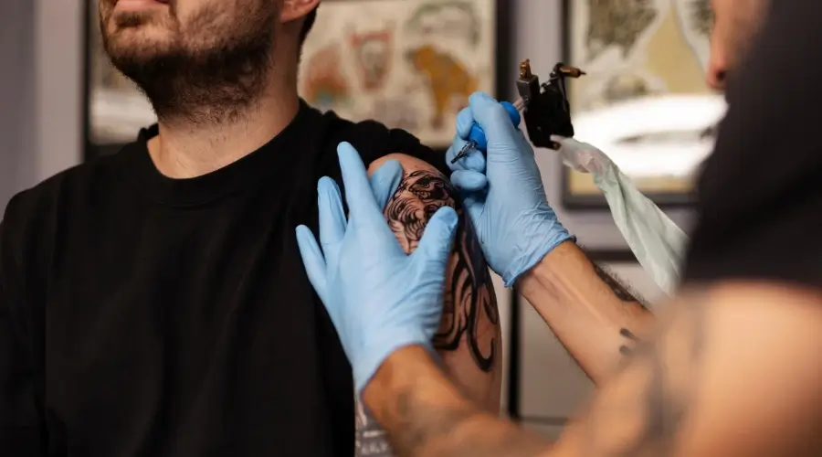 Side view of a man tattooing with gloves